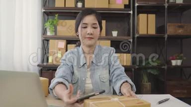 美丽的亚洲年轻企业家，女企业家，中小企业检查产品的股票扫描QR代码，在家工作。